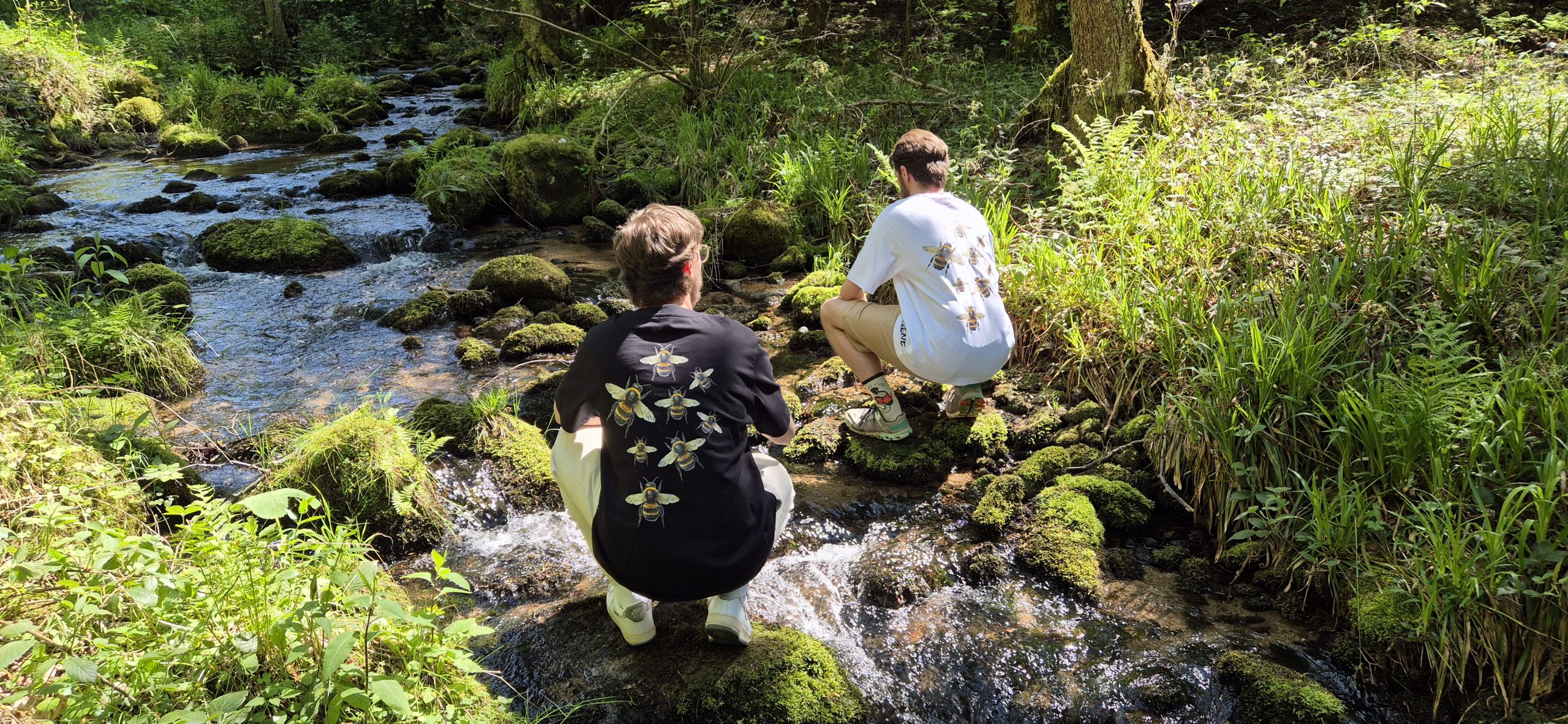 two people sitting on rocks in a stream